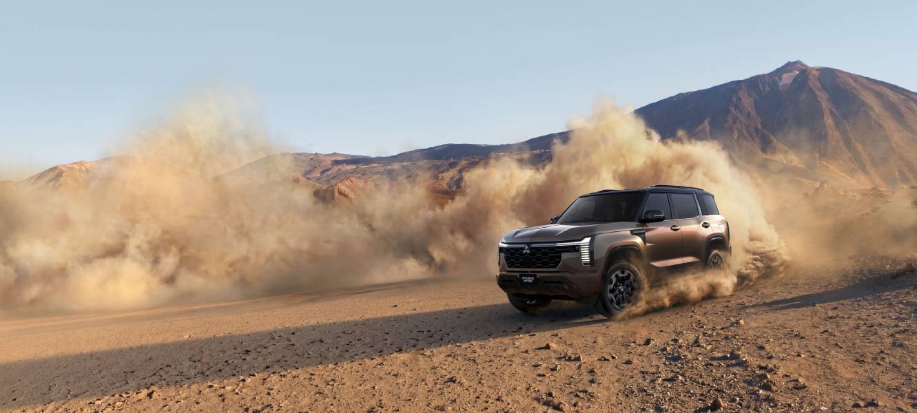 Novo Mitsubishi Pajero marrom andando na terra